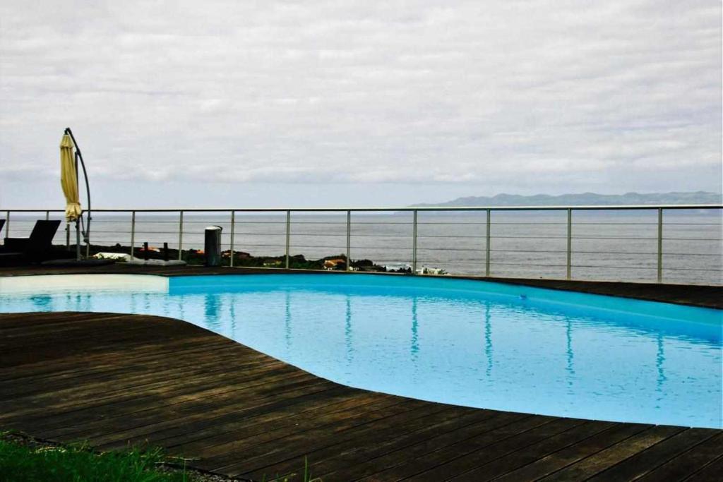 a swimming pool on a balcony with the ocean in the background at A Casa do Ouvidor in São Roque do Pico