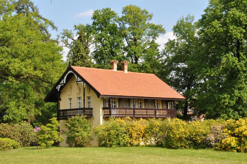 a small house with an orange roof in a field at Kavalierhaus im Rhododendronpark Kromlau in Gablenz