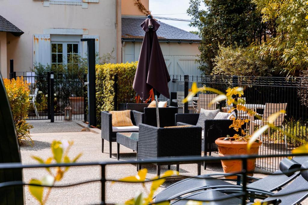 un groupe de chaises et un parasol sur une terrasse dans l'établissement Hôtel Villa Flornoy Pornichet Baie de la Baule, à Pornichet