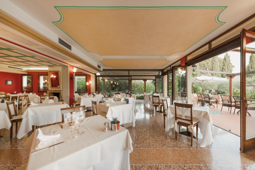 restauracja z białymi stołami, krzesłami i oknami w obiekcie Appartamento Le Vele w mieście Garda