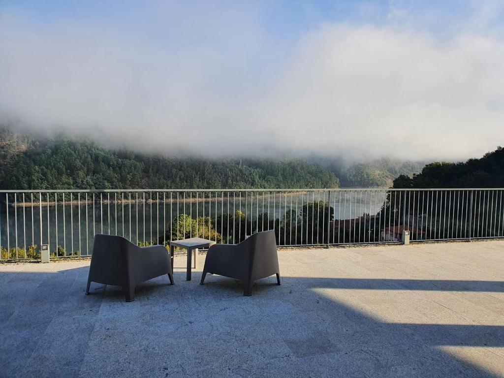 two chairs and a table with a view of a lake at Solar do Cávado in Vieira do Minho