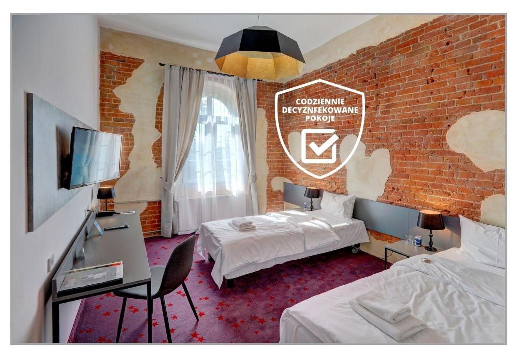 a hotel room with two beds and a brick wall at Koszary Arche Hotel in Góra Kalwaria