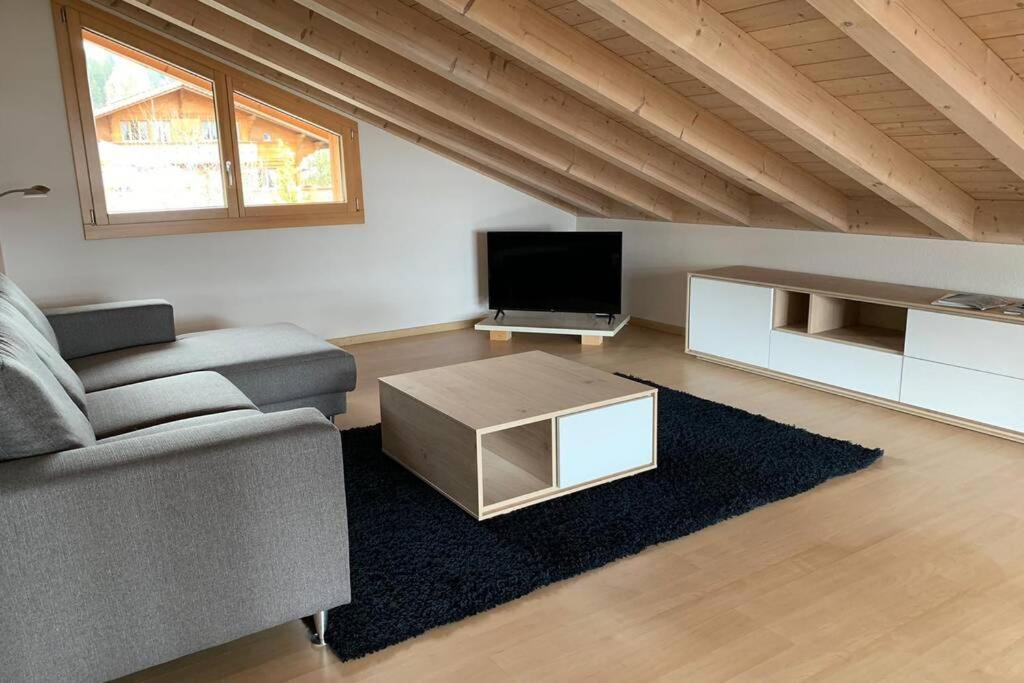 a living room with a couch and a tv at Région de GSTAAD, charmant chalet duplex de 80m2 in Zweisimmen