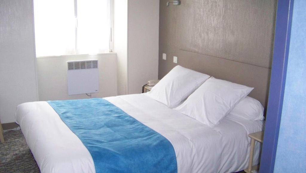 a bedroom with a bed with a blue and white blanket at Hotel Du Port in Concarneau