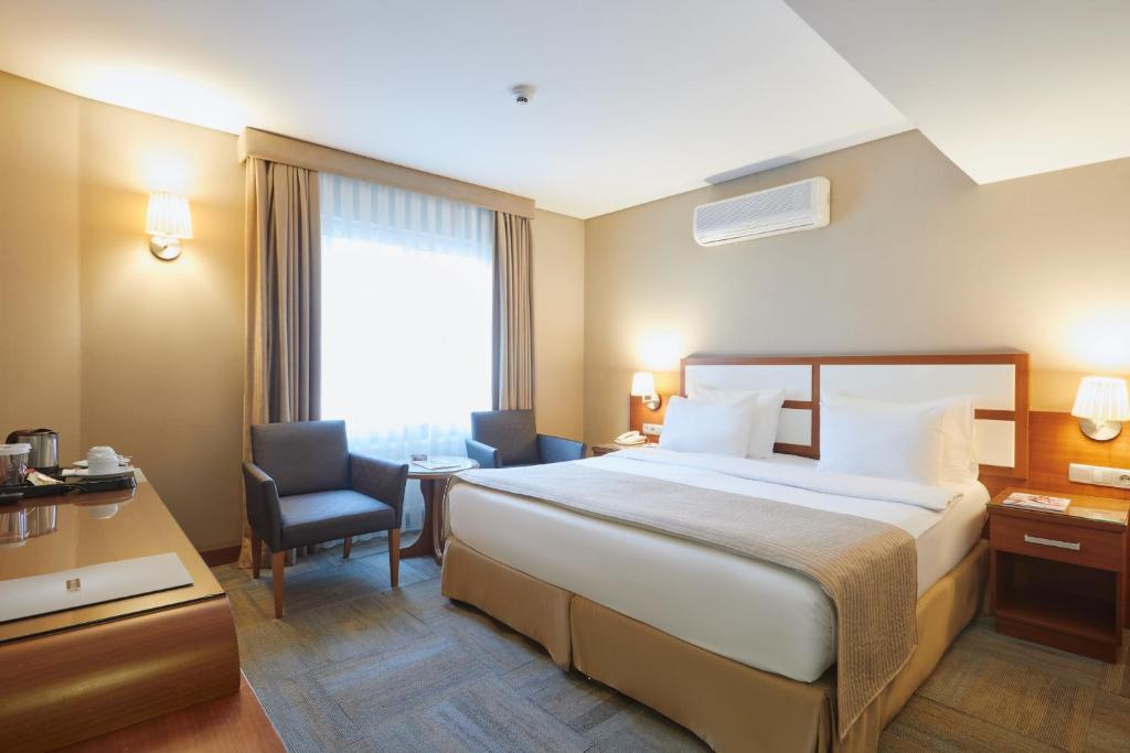 イスタンブールにあるポラットデミル ホテルの大きなベッドと椅子が備わるホテルルームです。