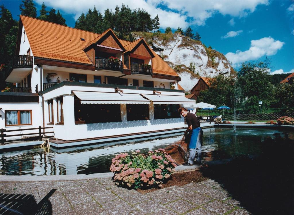 um homem parado em frente a um edifício ao lado de uma piscina em Hotel Forellenhof em Pottenstein