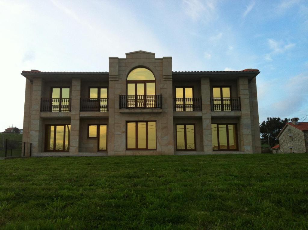 a large house on a grassy field at Apartamentos Turisticos Estrella del Alemar in Langre