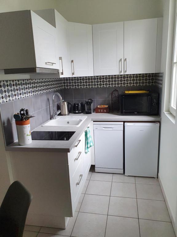 a kitchen with white cabinets and a sink and a microwave at appartement cosy au calme et en centre ville in Aix-les-Bains