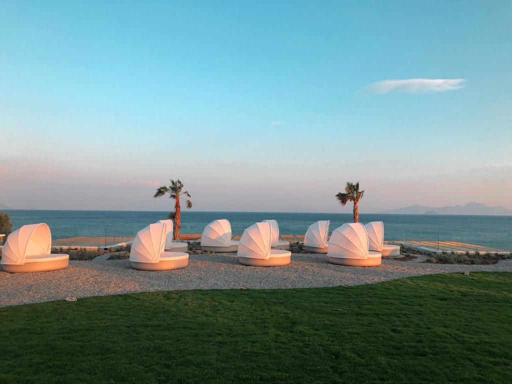 a group of white chairs sitting on the beach at Mitsis Norida in Kardamaina