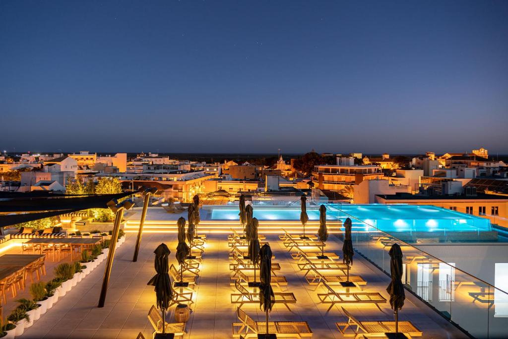 a view of a building with a pool at night at 3HB Faro in Faro