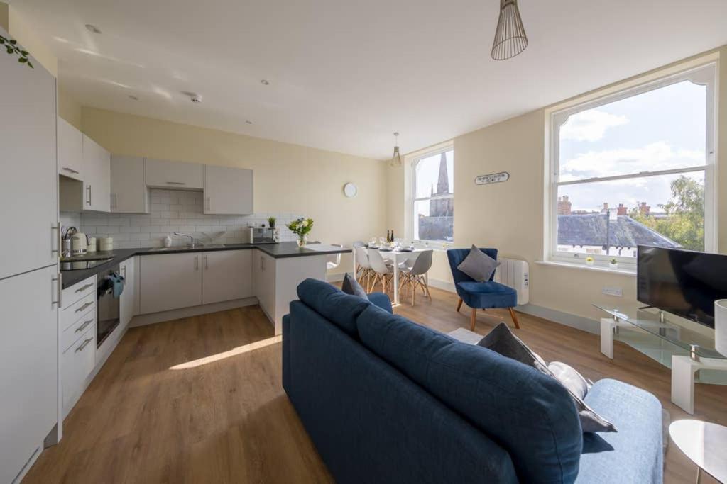 a living room with a blue couch and a kitchen at Apartment 5, Isabella House, Aparthotel, By RentMyHouse in Hereford