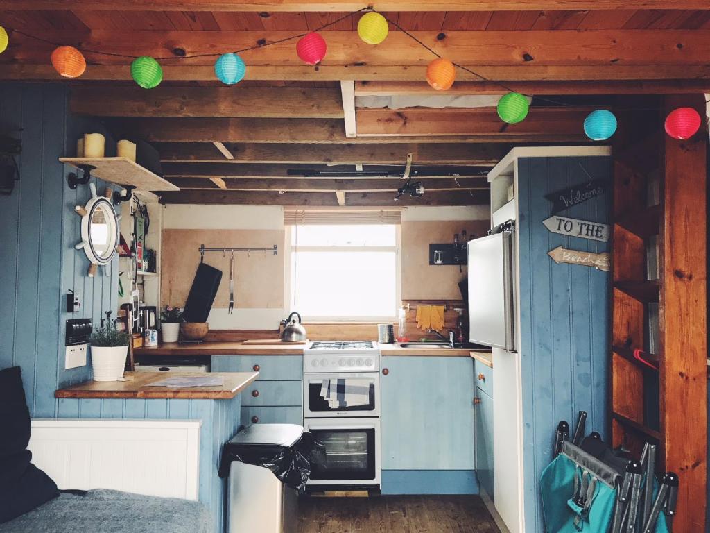 a kitchen with a stove and a refrigerator at Stargazing Beach Hut on Mudeford Sandbank with wake up sea views in Christchurch