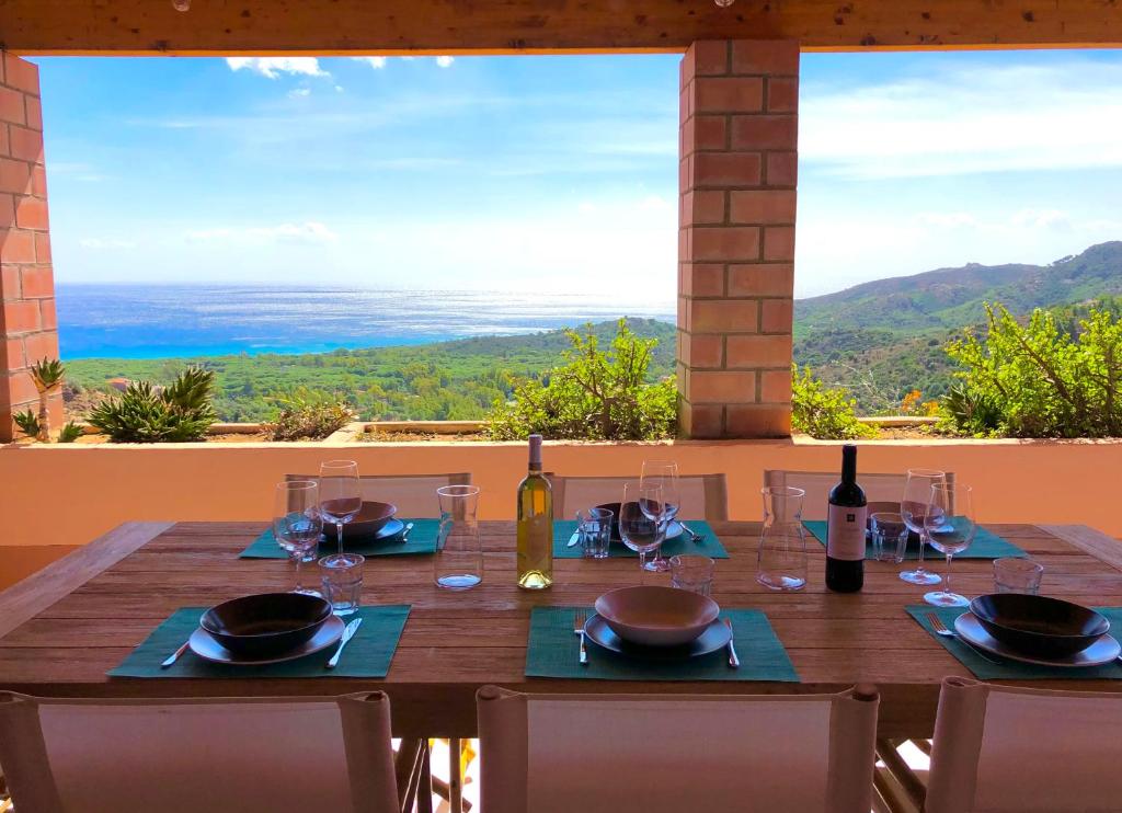 een houten tafel met wijnglazen en uitzicht op de oceaan bij LA VEDETTA dell’Eden by KlabHouse in Domus de Maria