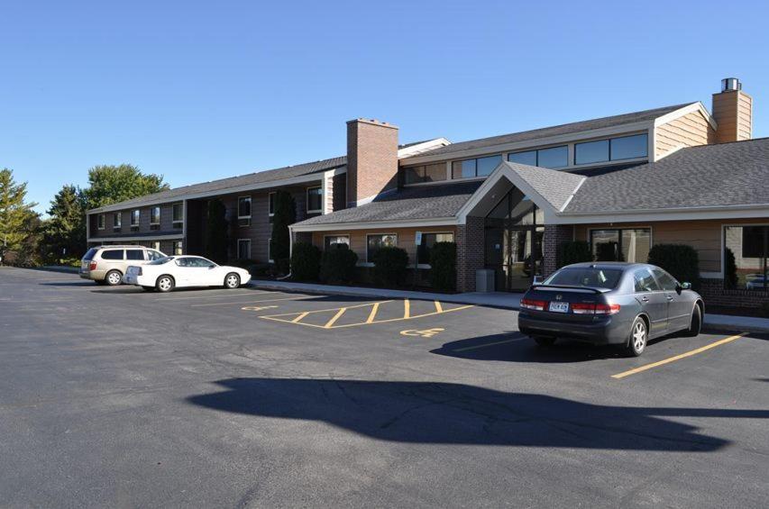 a parking lot with cars parked in front of a building at AmericInn by Wyndham Plymouth in Plymouth