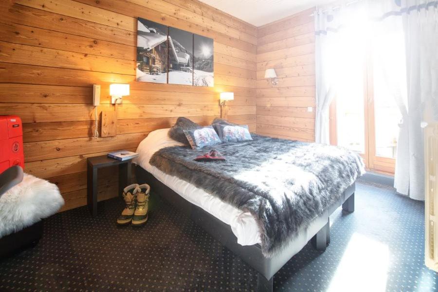 een slaapkamer met een bed in een houten kamer bij ALPINA LODGE VANOISE ex hotel du soleil in Aussois