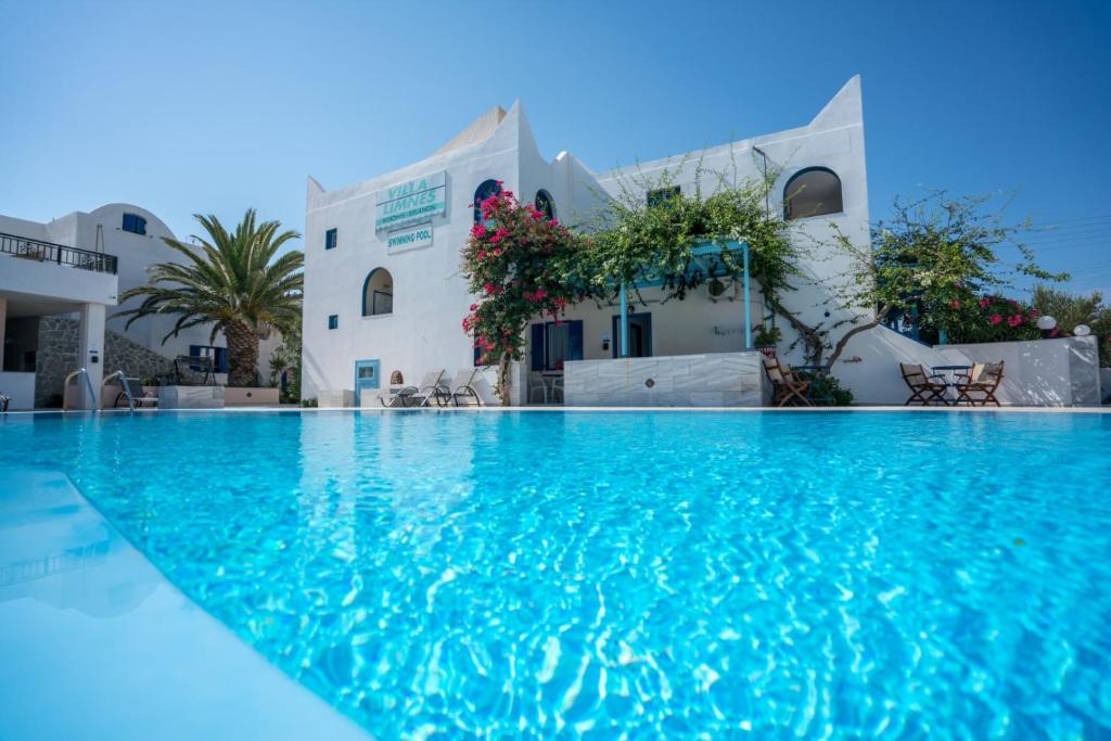 a swimming pool in front of a building at Villa Limnes in Perissa