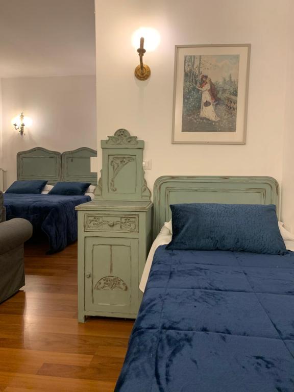 una camera con 2 letti con lenzuola blu e un comò di Le stanze di Anna Rita all'Arco Polinori a Foligno