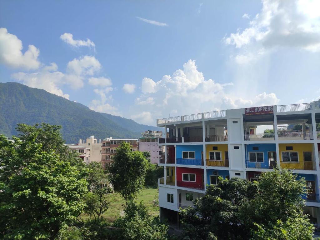 a building with colorful windows with a mountain in the background at Hill Hoppers Hotel in Rishīkesh