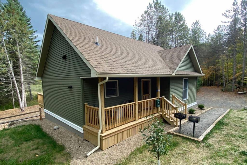 a green house with a porch and a deck at Beaver Brook Chalet in Wilmington