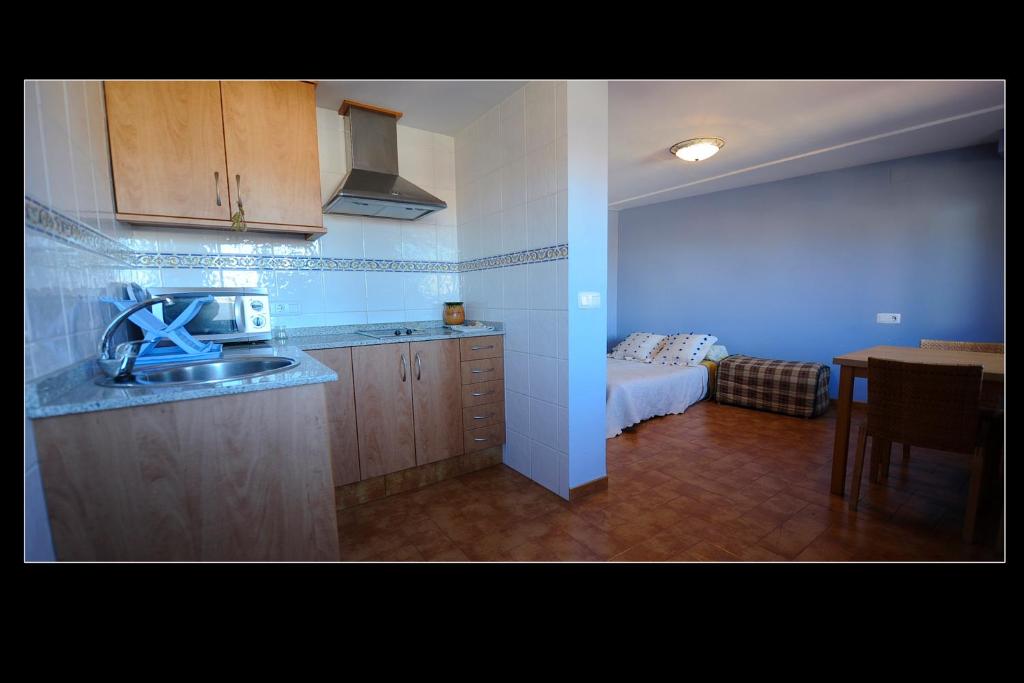 cocina con fregadero y habitación con cama en Apartamentos Rurales San Juan en Castellnovo