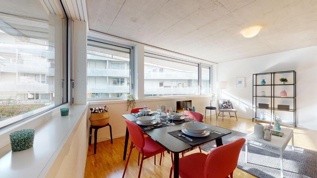 a dining room with a table and red chairs at Bright and luminous 1 bedroom flat in downtown in Sion