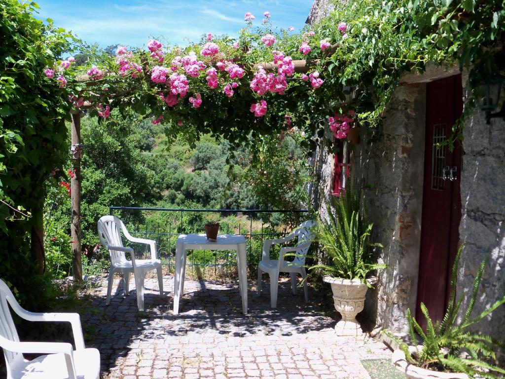 eine Terrasse mit einem Tisch, Stühlen und rosa Blumen in der Unterkunft My Room – Villa Vina ® - TER in Monchique