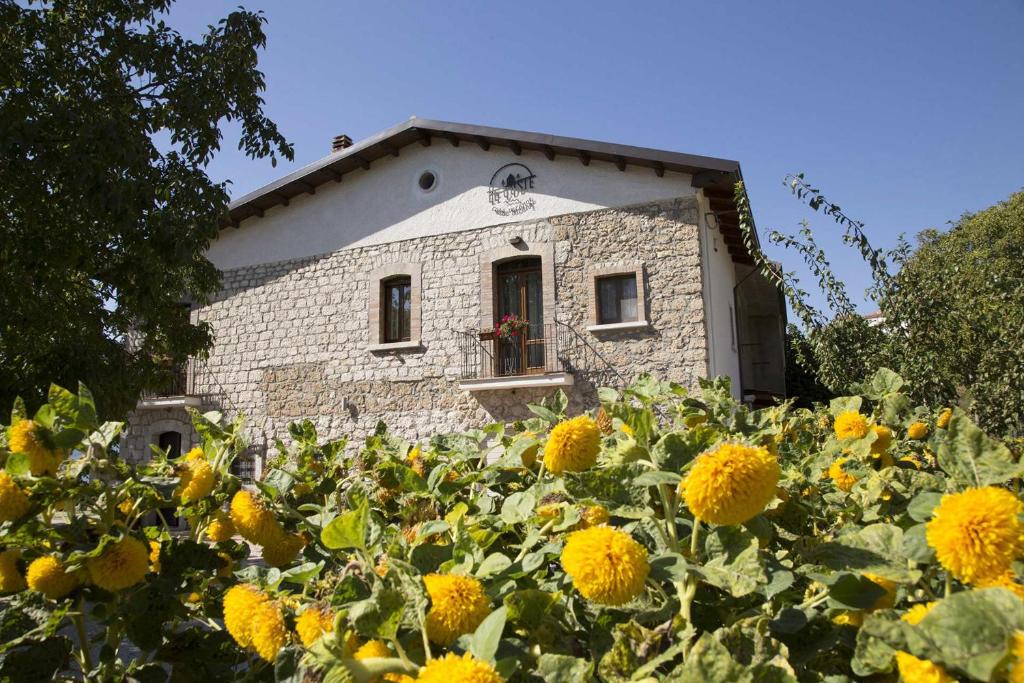 a building behind a field of yellow flowers at Le Coste Affittacamere in San Lupo