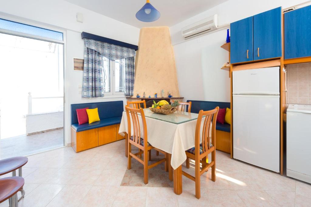 a kitchen with blue cabinets and a table with chairs at Stegna Sunny-Beach in Archangelos