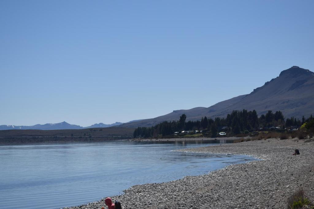 a person sitting on a beach next to the water at Montalto in Dina Huapi