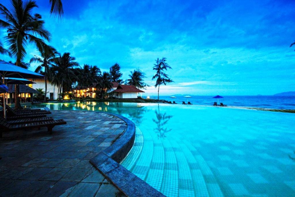 a swimming pool next to a beach at night at Sutra Beach Resort, Terengganu in Batu Rakit