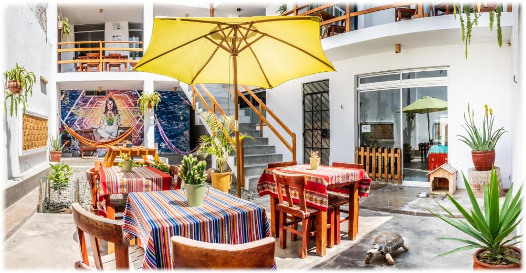 a patio with two tables and a yellow umbrella at ATMA Hostel & Yoga in Huanchaco
