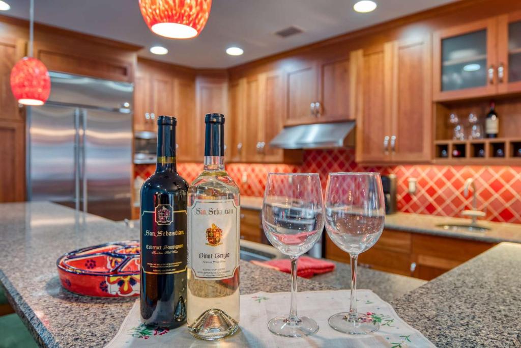 two wine bottles and two wine glasses on a kitchen counter at St. George Street Apartment in Saint Augustine