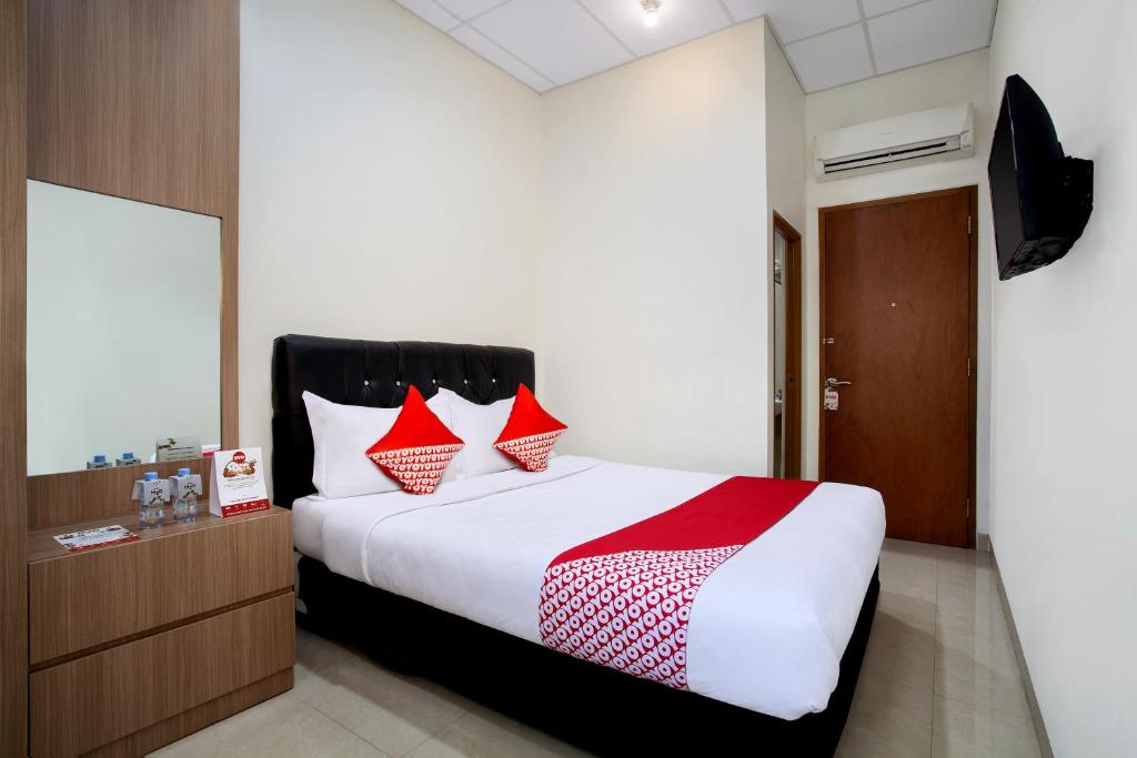 1 dormitorio con 1 cama grande con almohadas rojas en Capital O 106 Sarkawi Residence en Yakarta