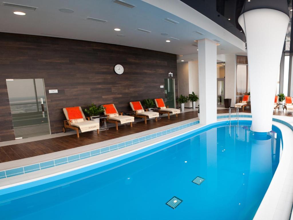 uma piscina no átrio do hotel com cadeiras em Vysotsky Hotel em Ecaterimburgo