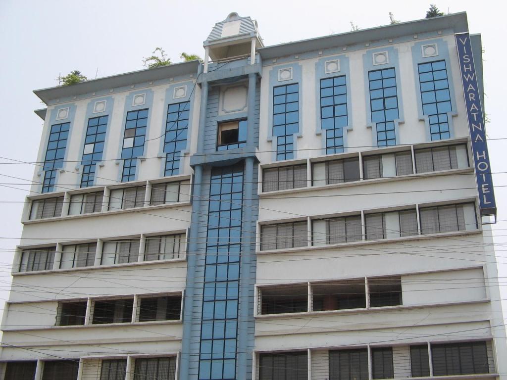 a tall white building with a blue sign on it at Vishwaratna Hotel in Guwahati