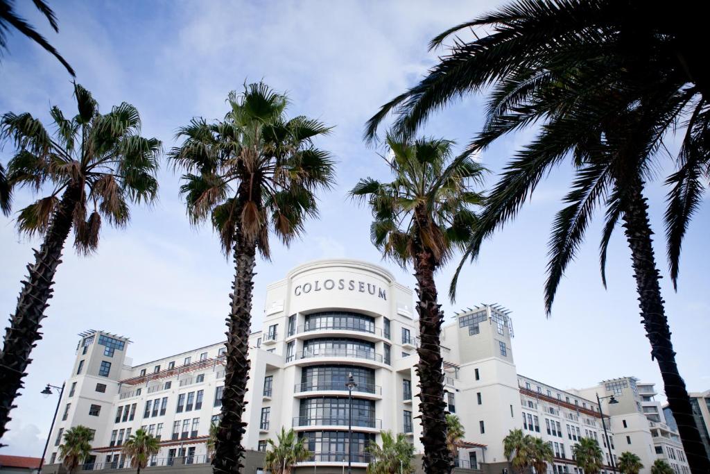 een wit gebouw met palmbomen ervoor bij Colosseum Luxury Hotel in Kaapstad