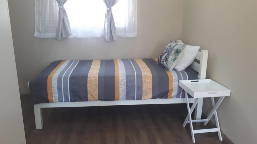 a small bedroom with a bed and a white table at Relax in Aberdeen in Johannesburg