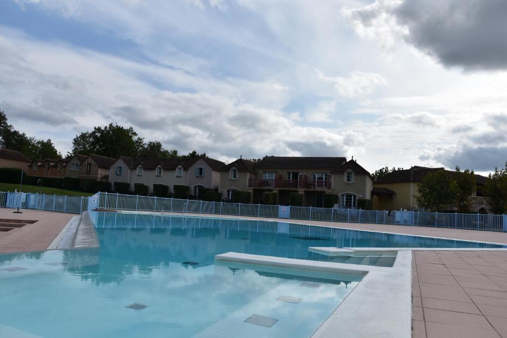 a large swimming pool with blue water and houses at Appartement avec vue magnifique sur le Lac de Monflanquin in Monflanquin