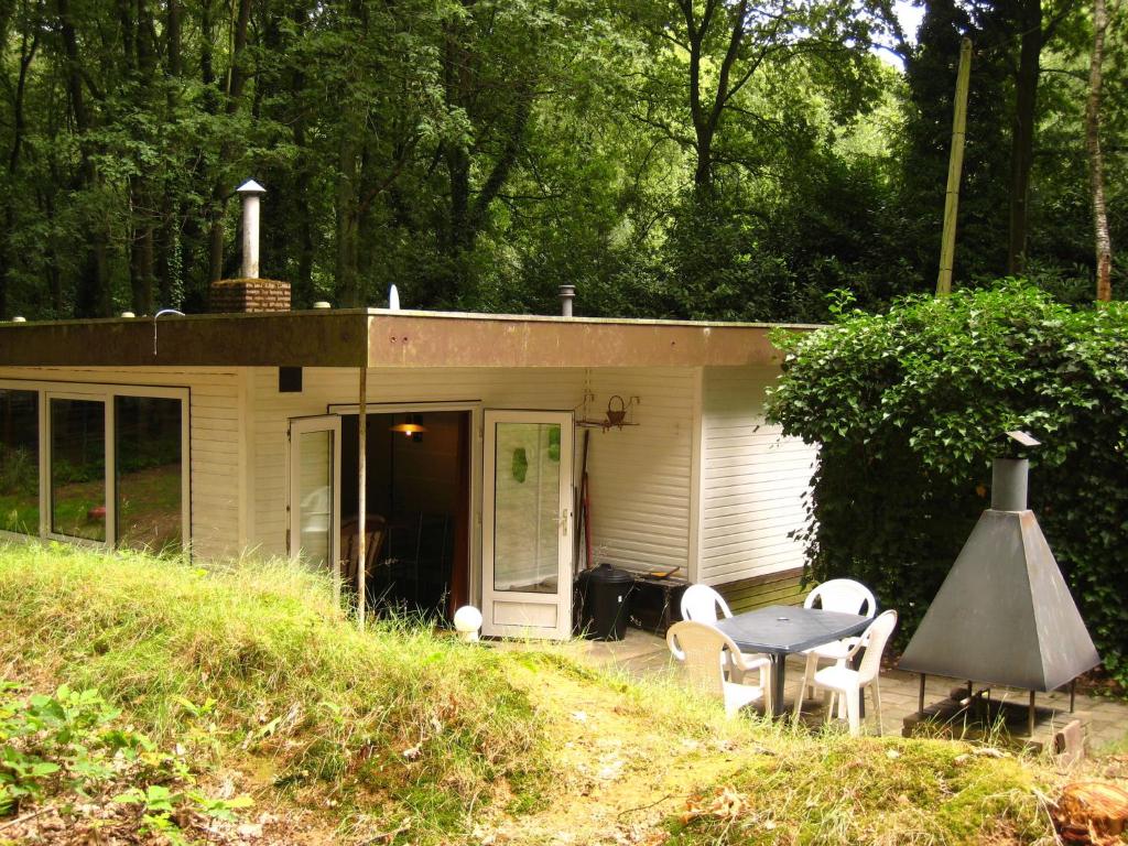 uma pequena casa com uma mesa e cadeiras em frente em Peacefully situated chalet surrounded by woods em Lanklaar