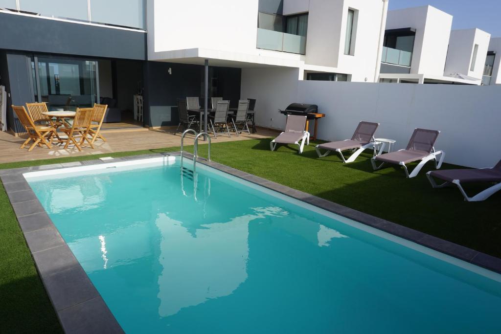 a swimming pool in a building with chairs and a table at Casa Soleada in La Oliva