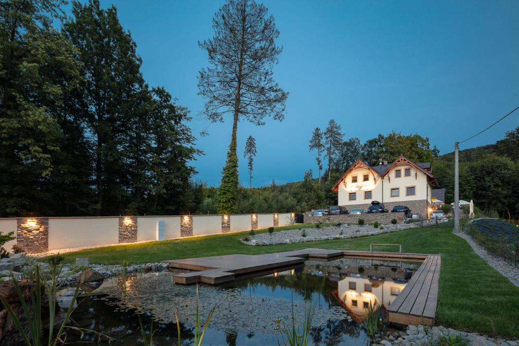 a home with a pond in front of a house at Penzion Na kraji lesa in Valašské Meziříčí