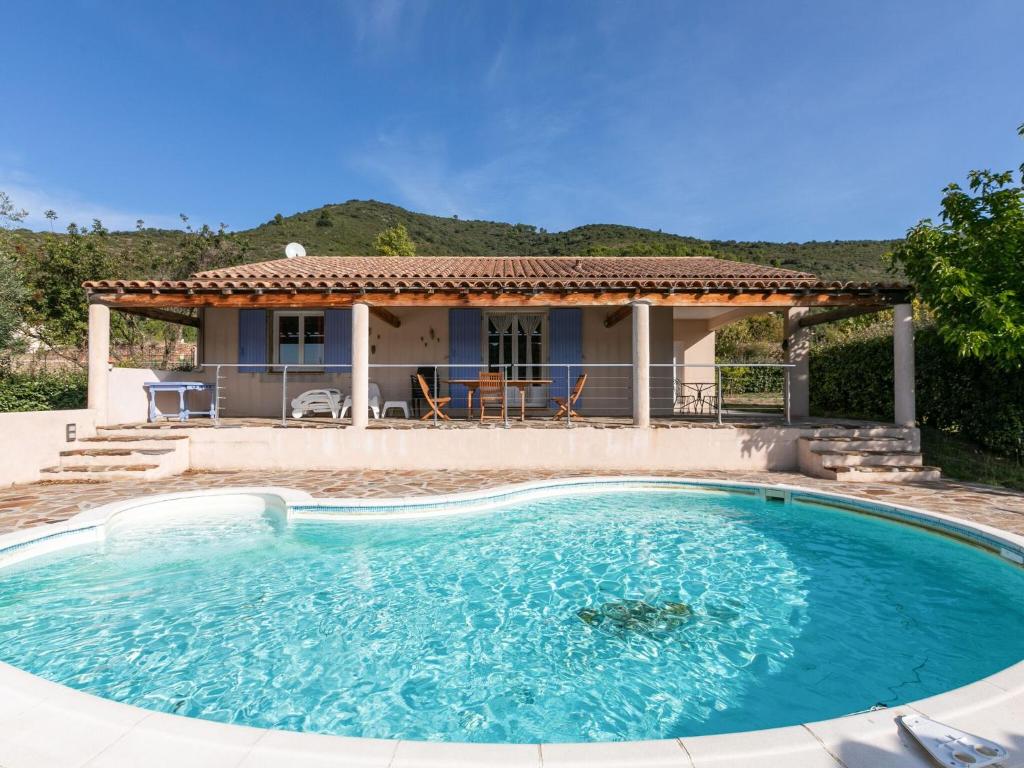 a house with a large swimming pool in front of a house at Cozy Villa in Roquebrun with Private Pool in Roquebrun