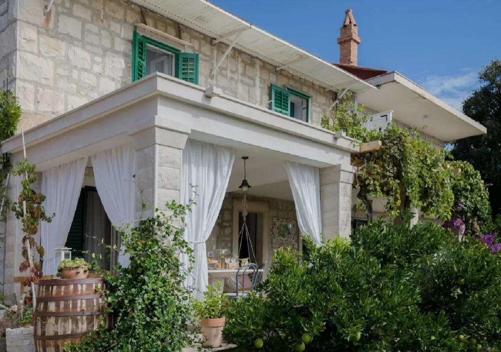 Selca的住宿－Apartments Jasna - peaceful area，一座带绿色百叶窗和门廊的石头房子