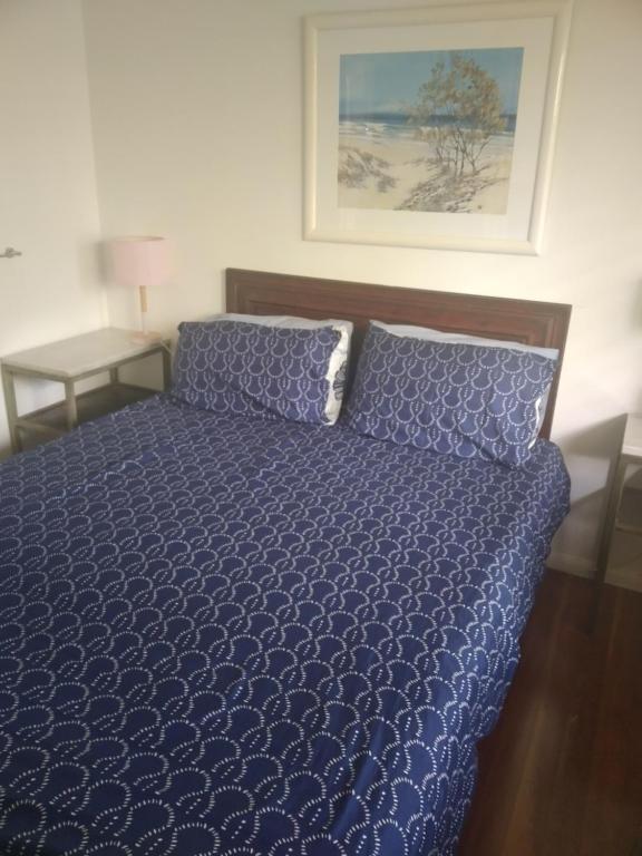 un letto con piumone blu in una camera da letto di Near to Everything Yet in a Rainforest setting a Tewantin