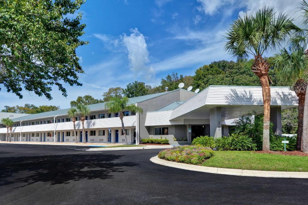 a large white building with palm trees in front of it at Studio 6 Extended Stay - Jacksonville, FL - Baymeadows in Sunbeam