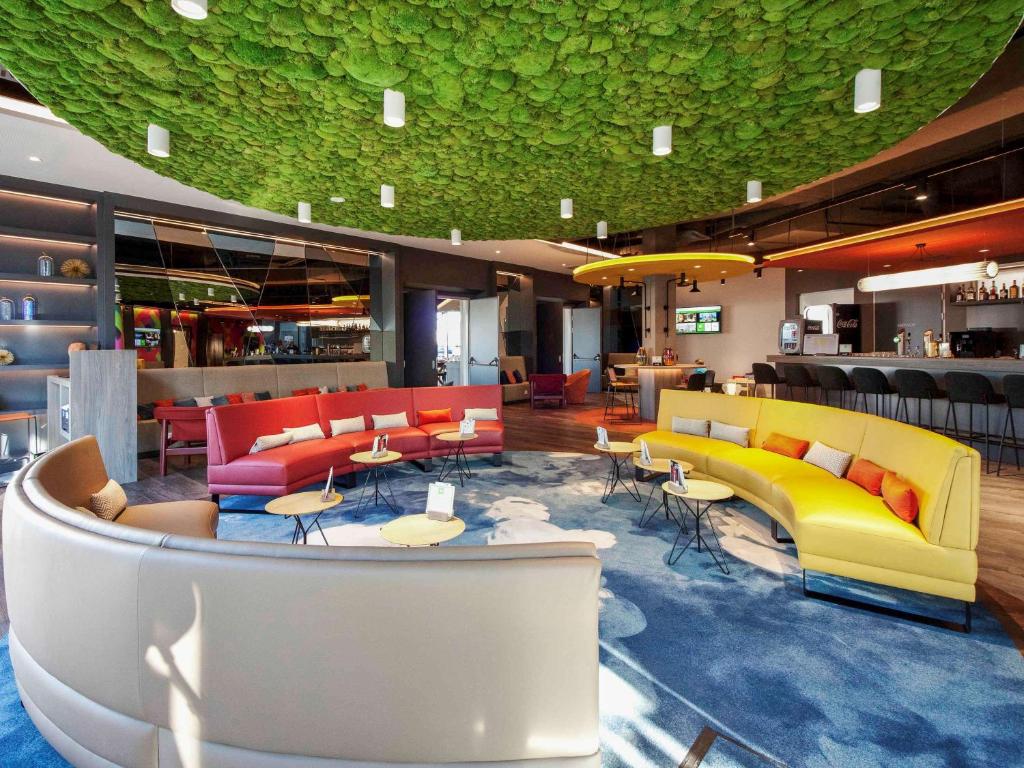 a lobby with colorful furniture and a bar at ibis Styles Parndorf Neusiedler See in Parndorf