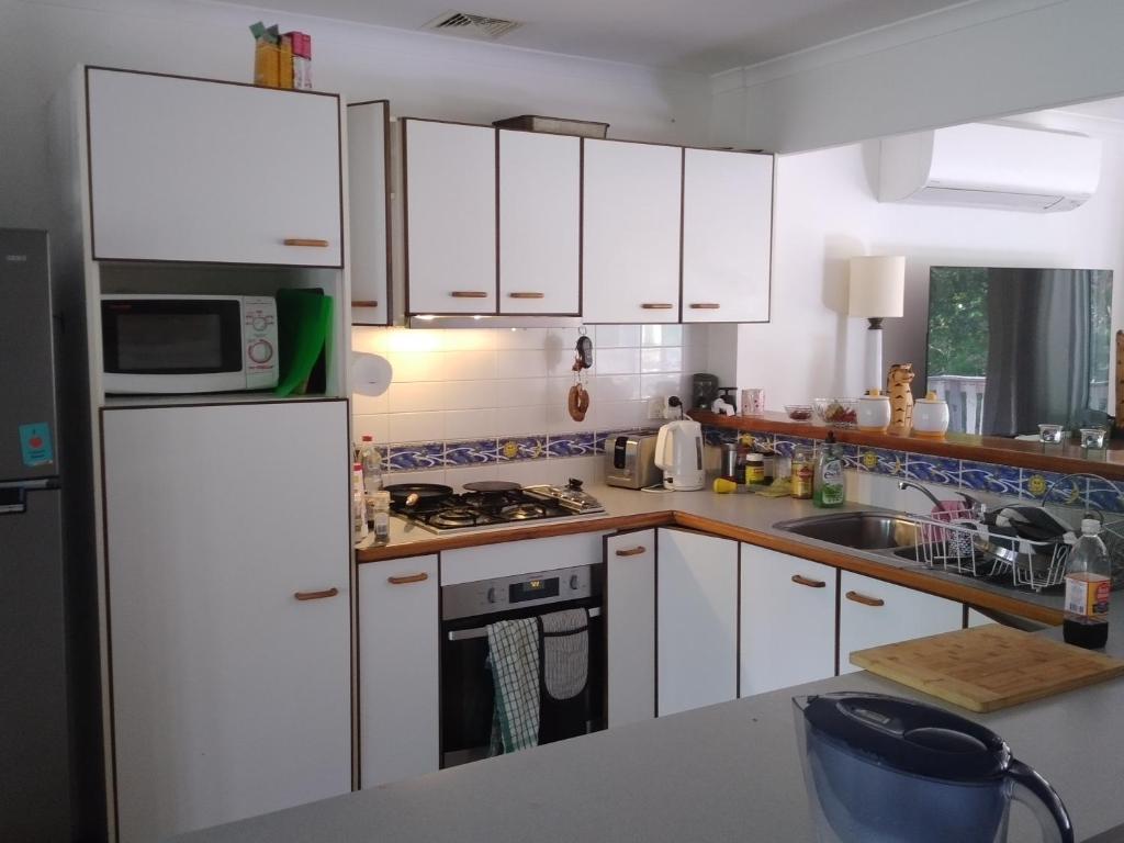 una cucina con armadietti bianchi e frigorifero bianco di Near to Everything Yet in a Rainforest setting a Tewantin