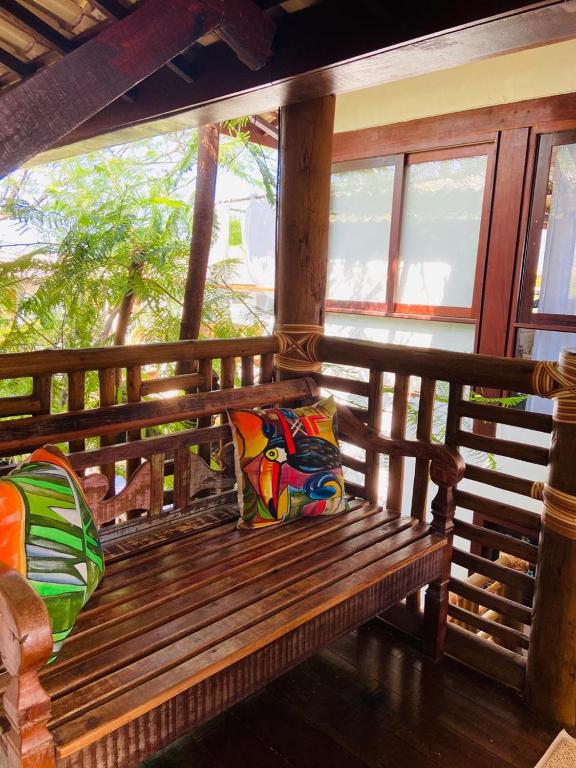 a wooden bench with two pillows on a porch at Pousada João Sol in Praia do Forte