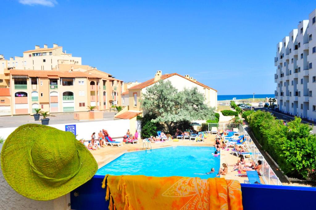 vistas a una piscina con sombrero en el balcón en Résidence Goélia Le Grand Bleu, en Le Barcarès