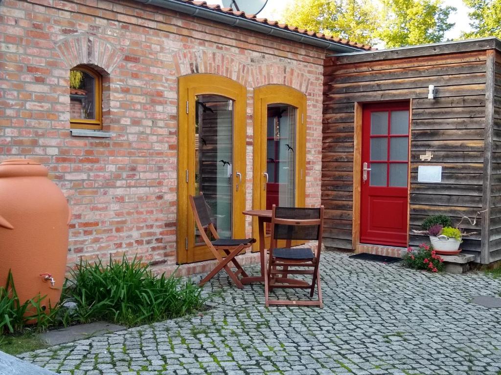 ein Haus mit einer roten Tür, einem Tisch und Stühlen in der Unterkunft Ferienwohnung Amende in Angermünde